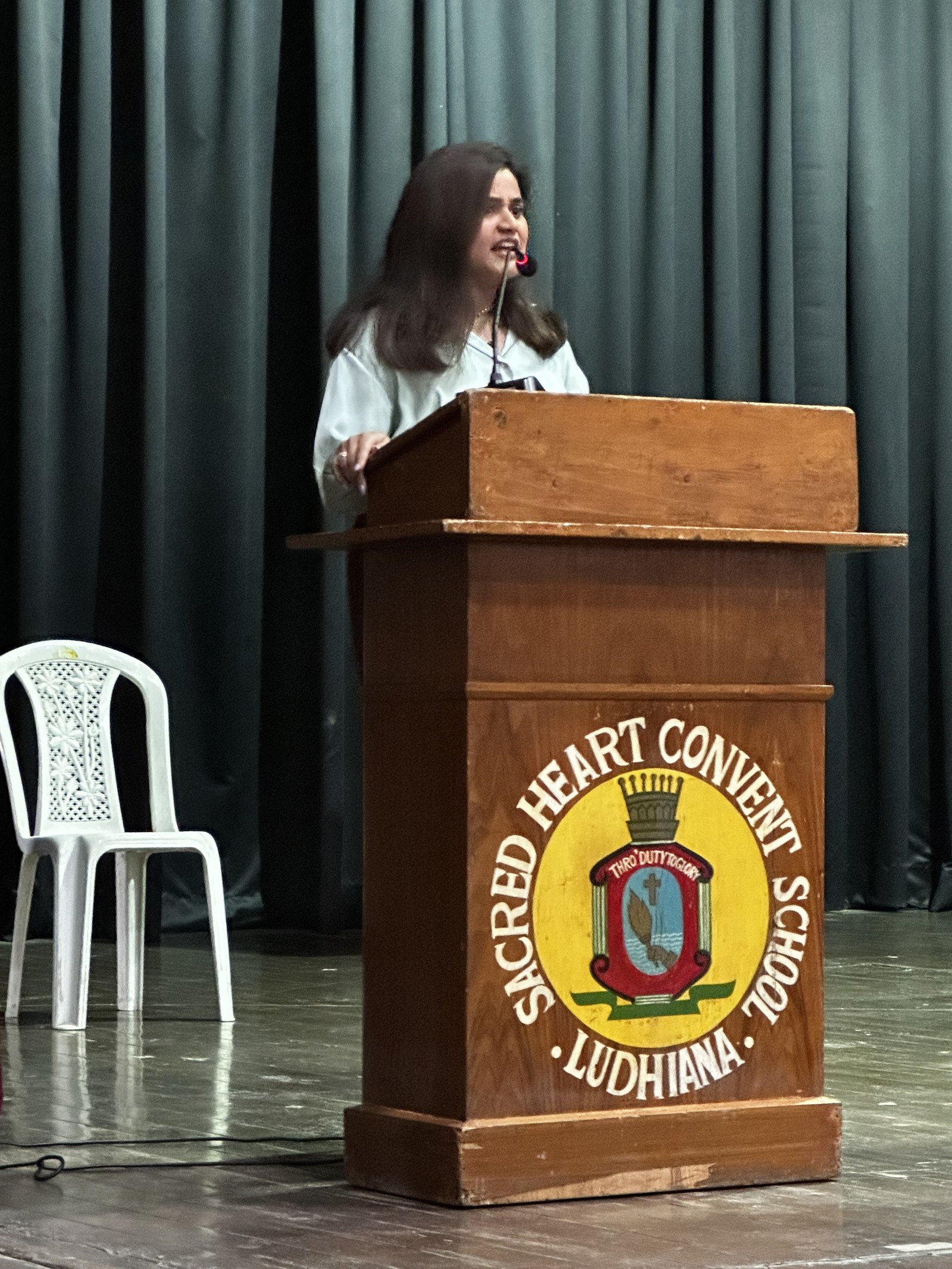 Coach Shavy Jain speaking at the podium at Sacred Heart Convent School, Ludhiana